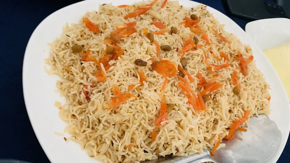 A plate of rice with carrots and raisins